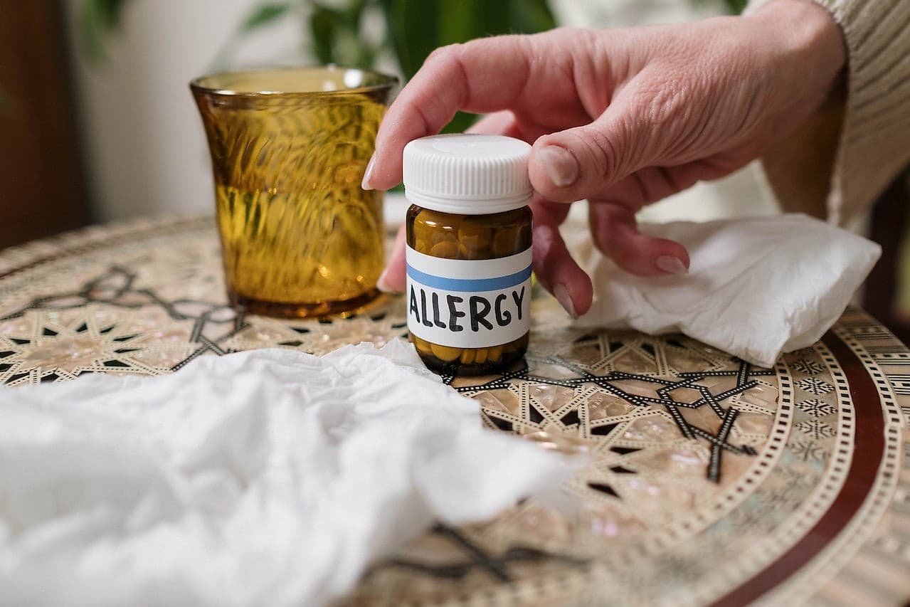 A person picking up allergy medicine, showing that indoor concrete floors are better than carpets for people with allergies.